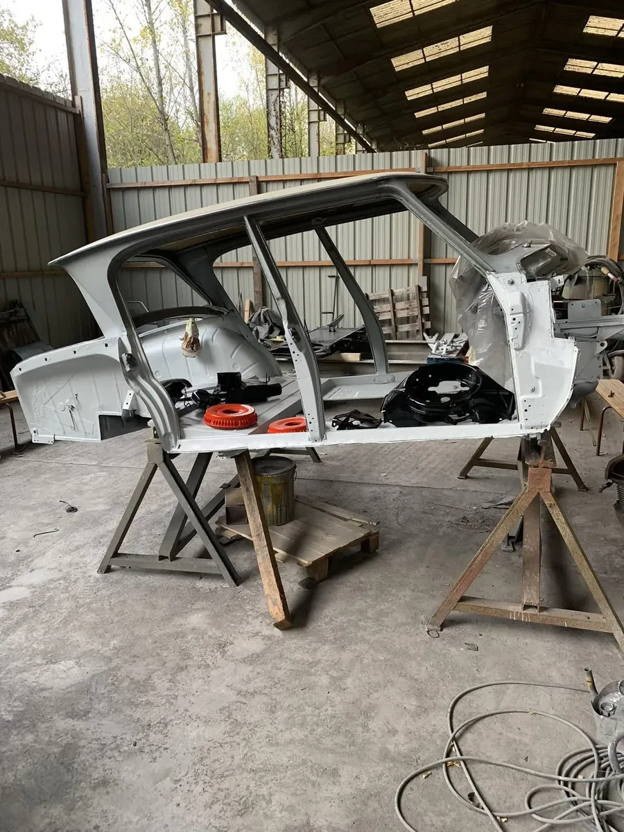Carrosserie de voiture mise à nu et apprêtée sur tréteaux dans l'atelier