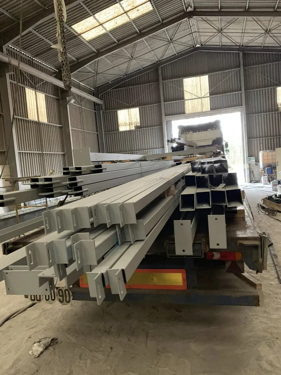 Poutres et profilés métalliques peints en gris dans l'atelier KLM, prêts à être chargés sur un camion